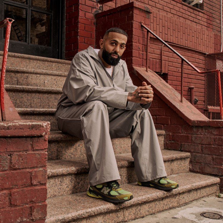 Eladio sitting down by himself on the steps with his hands folded.